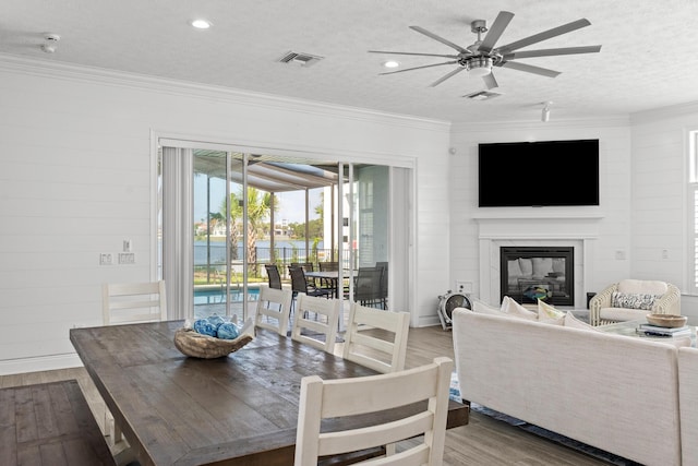 72 Tranquility Ln, Destin, FL 32541 - dining room with wood finished floors, ceiling fan, ornamental molding, a glass covered fireplace, and a textured ceiling