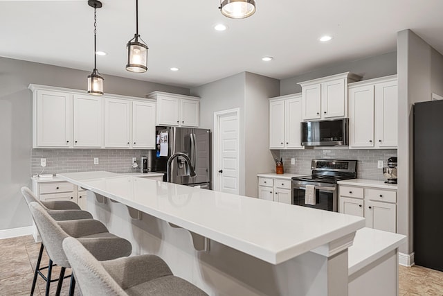 801 Playground Rd, Fort Walton Beach, FL 32547 - kitchen featuring appliances with stainless steel finishes, a breakfast bar area, tasteful backsplash, white cabinets, and recessed lighting