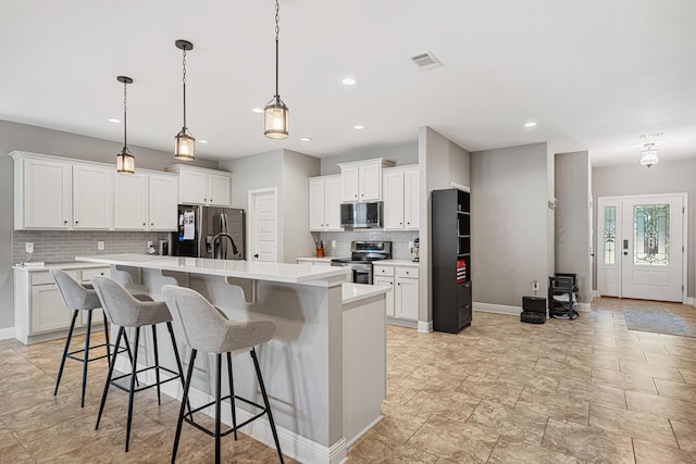 801 Playground Rd, Fort Walton Beach, FL 32547 - kitchen featuring appliances with stainless steel finishes, decorative backsplash, light countertops, a center island with sink, and baseboards