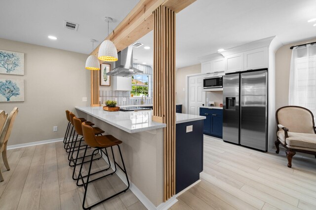 112 Meigs Dr, Shalimar, FL 32579 - kitchen with stainless steel appliances, range hood, a kitchen breakfast bar, light wood finished floors, and tasteful backsplash