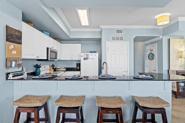 16819 Front Beach Rd Unit 2300, Panama City Beach, FL 32413 - kitchen featuring white appliances, ornamental molding, a peninsula, white cabinets, and a kitchen bar