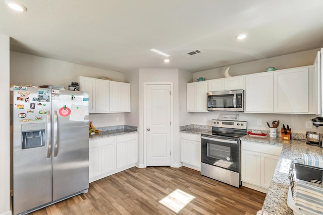756 Graysen Ln, Defuniak Springs, FL 32435 - kitchen with stainless steel appliances, recessed lighting, light wood-style floors, white cabinets, and light stone counters