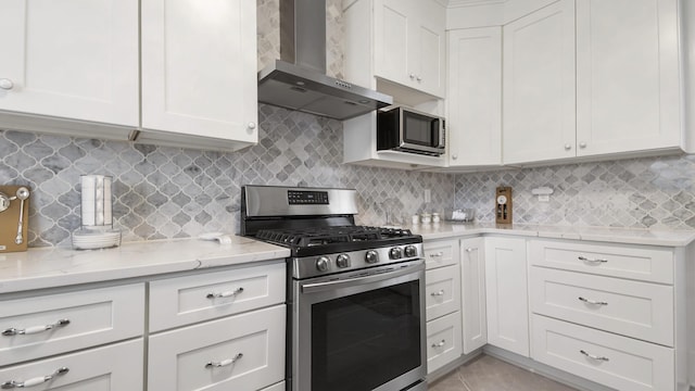 119 E Live Oak Ave, Defuniak Springs, FL 32435 - kitchen featuring stainless steel gas range oven, wall chimney exhaust hood, white cabinets, and light stone countertops