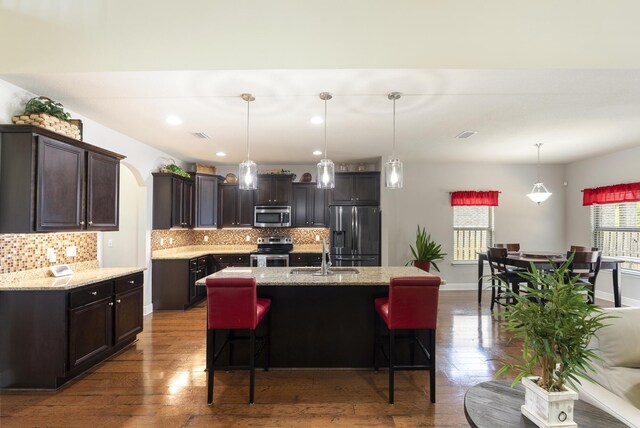 170 Windchime Way, Freeport, FL 32439 - kitchen with appliances with stainless steel finishes, a sink, hardwood / wood-style floors, dark brown cabinets, and tasteful backsplash