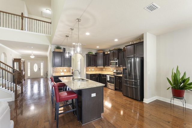 170 Windchime Way, Freeport, FL 32439 - kitchen with appliances with stainless steel finishes, a sink, decorative backsplash, a center island with sink, and dark wood-type flooring