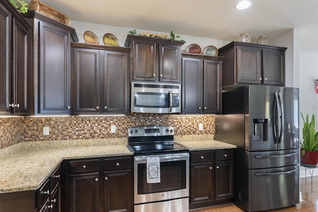 170 Windchime Way, Freeport, FL 32439 - kitchen with stainless steel appliances, dark brown cabinetry, light stone counters, and decorative backsplash
