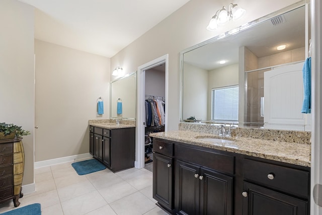 170 Windchime Way, Freeport, FL 32439 - bathroom featuring two vanities, tile patterned flooring, tiled shower, baseboards, and a walk in closet