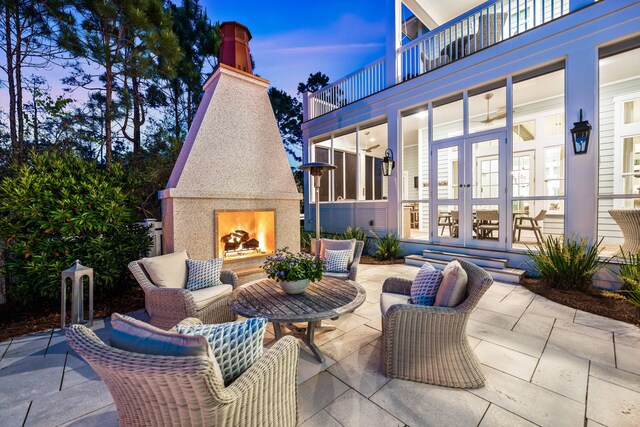 667 E Royal Fern Way, Santa Rosa Beach, FL 32459 - patio terrace at dusk with a lit fireplace, french doors, a balcony, and a patio