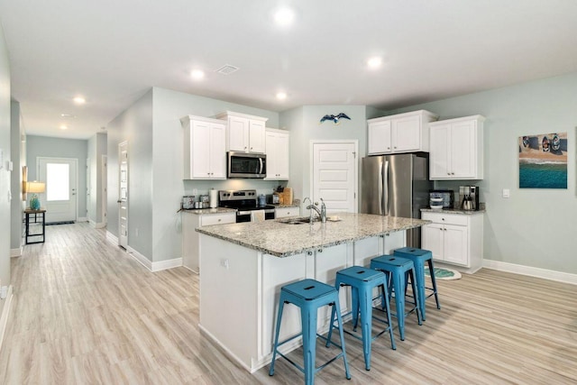718 Backwater Rd, Port St Joe, FL 32456 - kitchen with stainless steel appliances, a sink, baseboards, light wood finished floors, and white cabinets