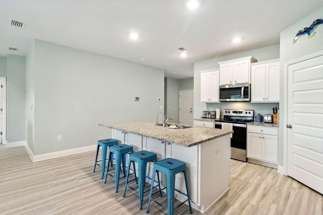 718 Backwater Rd, Port St Joe, FL 32456 - kitchen with stainless steel appliances, a sink, light wood finished floors, a kitchen island with sink, and recessed lighting