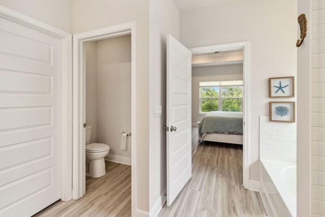 718 Backwater Rd, Port St Joe, FL 32456 - full bath featuring wood finished floors, toilet, a tub to relax in, baseboards, and ensuite bathroom