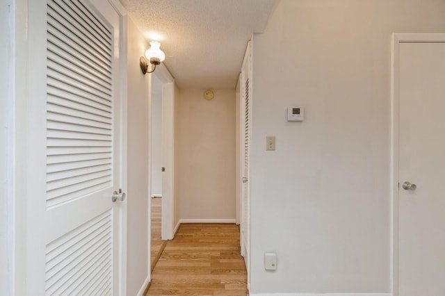 104 Country Club Dr Unit 104, Niceville, FL 32578 - hallway with light wood-type flooring, a textured ceiling, and baseboards
