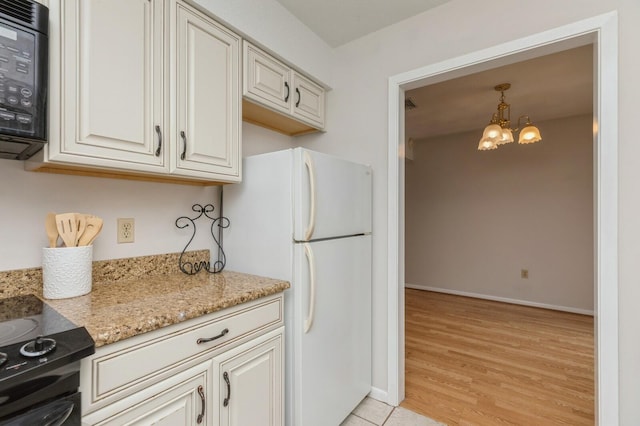 104 Country Club Dr Unit 104, Niceville, FL 32578 - kitchen with freestanding refrigerator, a chandelier, light stone countertops, baseboards, and light wood-style flooring