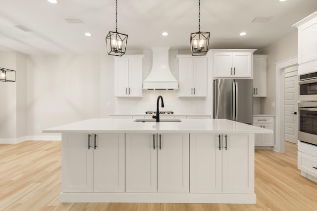 335 J Hunters Way S, Freeport, FL 32439 - kitchen featuring premium range hood, stainless steel appliances, backsplash, light countertops, and a center island with sink