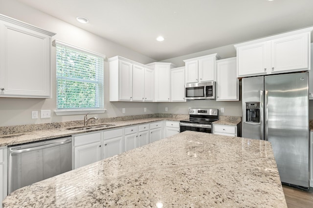 74 Tranquility Ln, Santa Rosa Beach, FL 32459 - kitchen with stainless steel appliances, white cabinets, light stone counters, recessed lighting, and wood finished floors
