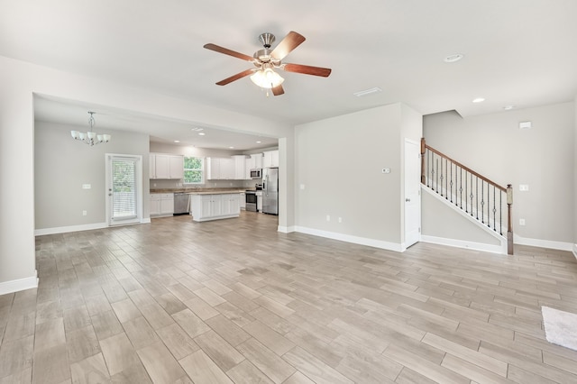 74 Tranquility Ln, Santa Rosa Beach, FL 32459 - unfurnished living room featuring a ceiling fan, light wood finished floors, a chandelier, stairway, and recessed lighting