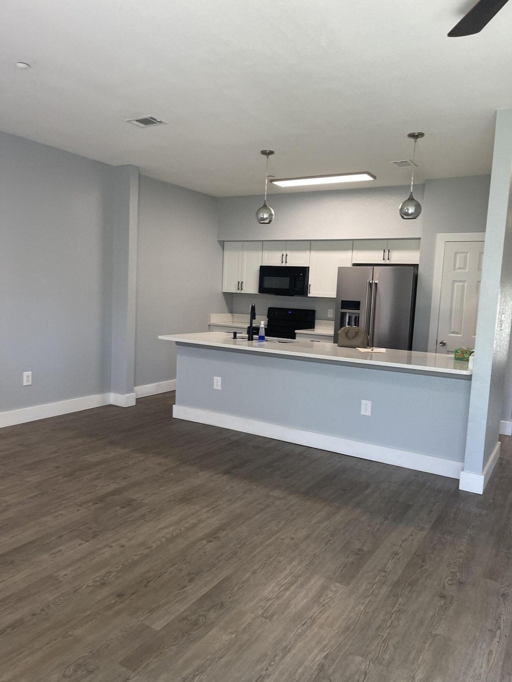 424 Ed St, Fort Walton Beach, FL 32547 - kitchen featuring stainless steel fridge, black microwave, dark wood finished floors, and light countertops