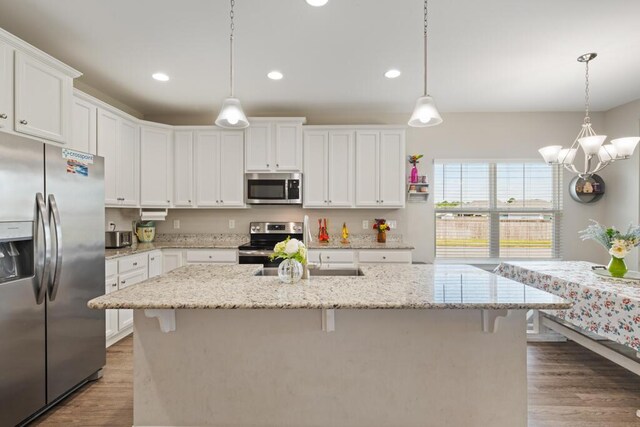 809 Whispering Creek Ave, Freeport, FL 32439 - kitchen featuring appliances with stainless steel finishes, wood finished floors, white cabinets, a kitchen bar, and recessed lighting
