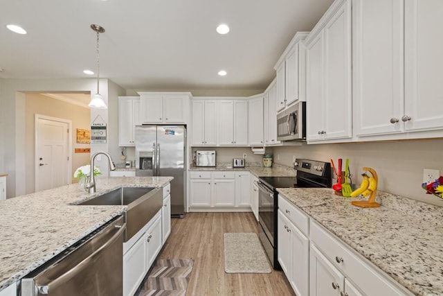 809 Whispering Creek Ave, Freeport, FL 32439 - kitchen featuring appliances with stainless steel finishes, a sink, white cabinetry, light wood-style floors, and hanging light fixtures