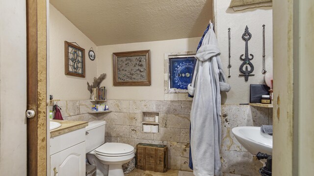 841 N 1st St, Defuniak Springs, FL 32433 - half bathroom with a textured ceiling, toilet, tile walls, vanity, and a wainscoted wall