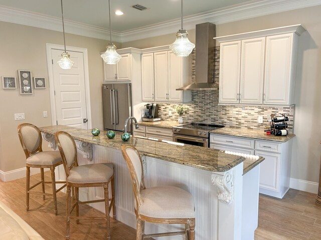 1976 Baytowne Loop, Miramar Beach, FL 32550 - kitchen with wall chimney range hood, stainless steel appliances, a breakfast bar area, light wood-style flooring, and white cabinetry