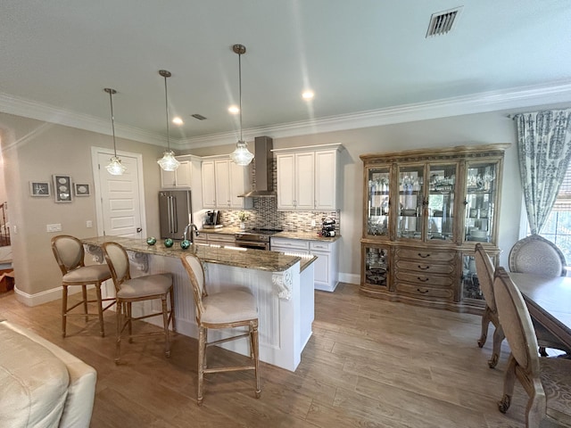 1976 Baytowne Loop, Miramar Beach, FL 32550 - kitchen featuring wall chimney exhaust hood, stainless steel range, a kitchen bar, a kitchen island with sink, and crown molding