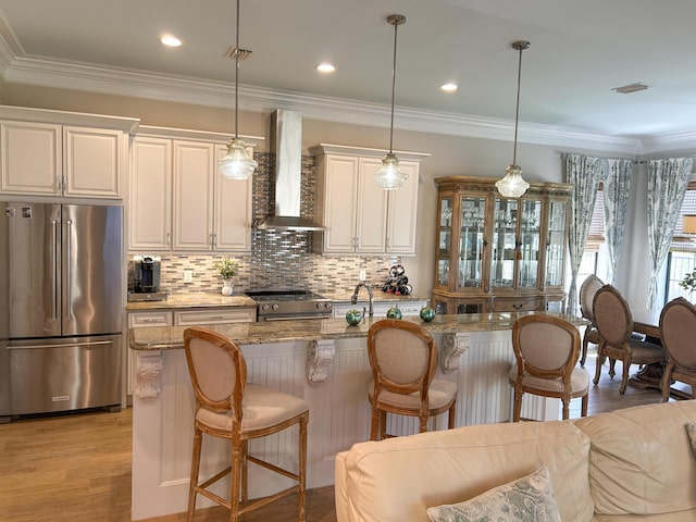 1976 Baytowne Loop, Miramar Beach, FL 32550 - kitchen with high end appliances, wall chimney range hood, a breakfast bar area, tasteful backsplash, and light stone countertops