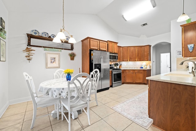 53 Concert Ct, Freeport, FL 32439 - kitchen featuring appliances with stainless steel finishes, a sink, decorative backsplash, brown cabinets, and arched walkways