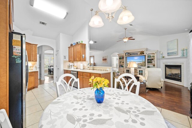 53 Concert Ct, Freeport, FL 32439 - dining area with arched walkways, a glass covered fireplace, vaulted ceiling, ceiling fan, and light tile patterned floors