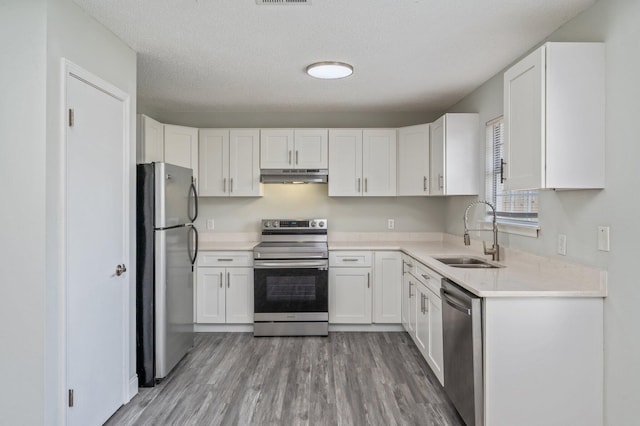 2129 Hillary Ln, Navarre, FL 32566 - kitchen with appliances with stainless steel finishes, under cabinet range hood, a sink, white cabinetry, and a textured ceiling