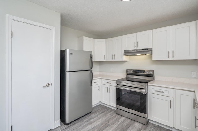 2129 Hillary Ln, Navarre, FL 32566 - kitchen with appliances with stainless steel finishes, under cabinet range hood, light wood-type flooring, light countertops, and white cabinetry