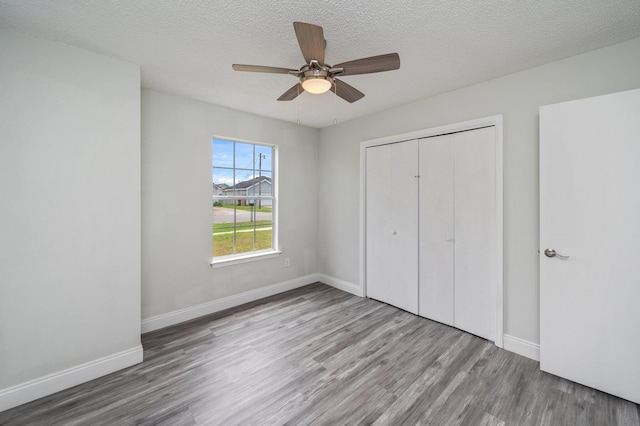 2129 Hillary Ln, Navarre, FL 32566 - unfurnished bedroom with wood finished floors, a closet, baseboards, a textured ceiling, and ceiling fan