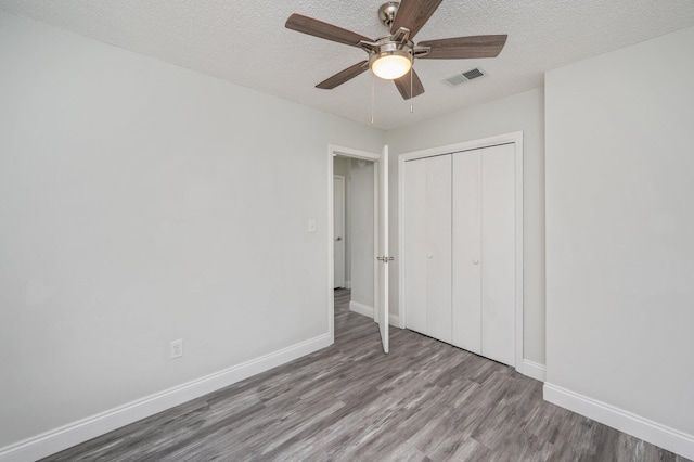 2129 Hillary Ln, Navarre, FL 32566 - unfurnished bedroom with wood finished floors, baseboards, a closet, a textured ceiling, and ceiling fan