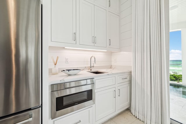 323 Pompano St, Inlet Beach, FL 32461 - kitchen with stainless steel fridge, light stone counters, white cabinetry, a sink, and wall oven