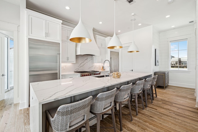 323 Pompano St, Inlet Beach, FL 32461 - kitchen with light wood finished floors, a sink, decorative backsplash, an island with sink, and white cabinetry