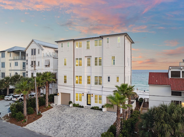 323 Pompano St, Inlet Beach, FL 32461 - property at dusk with decorative driveway, a garage, and a water view