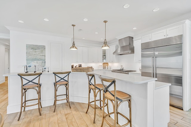 134 Norwood Dr Unit Ph1, Miramar Beach, FL 32550 - kitchen with built in refrigerator, wall chimney range hood, crown molding, white cabinets, and light countertops