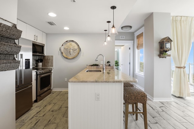 9800 Grand Sandestin Blvd Unit 5602/5604, Sandestin, FL 32550 - kitchen featuring appliances with stainless steel finishes, a sink, light wood finished floors, a breakfast bar, and white cabinetry