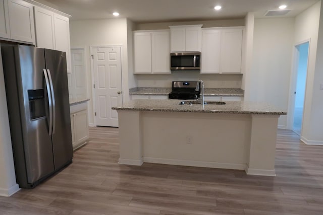 106 E Sky Way, Freeport, FL 32439 - kitchen with appliances with stainless steel finishes, recessed lighting, wood finished floors, a kitchen island with sink, and white cabinetry