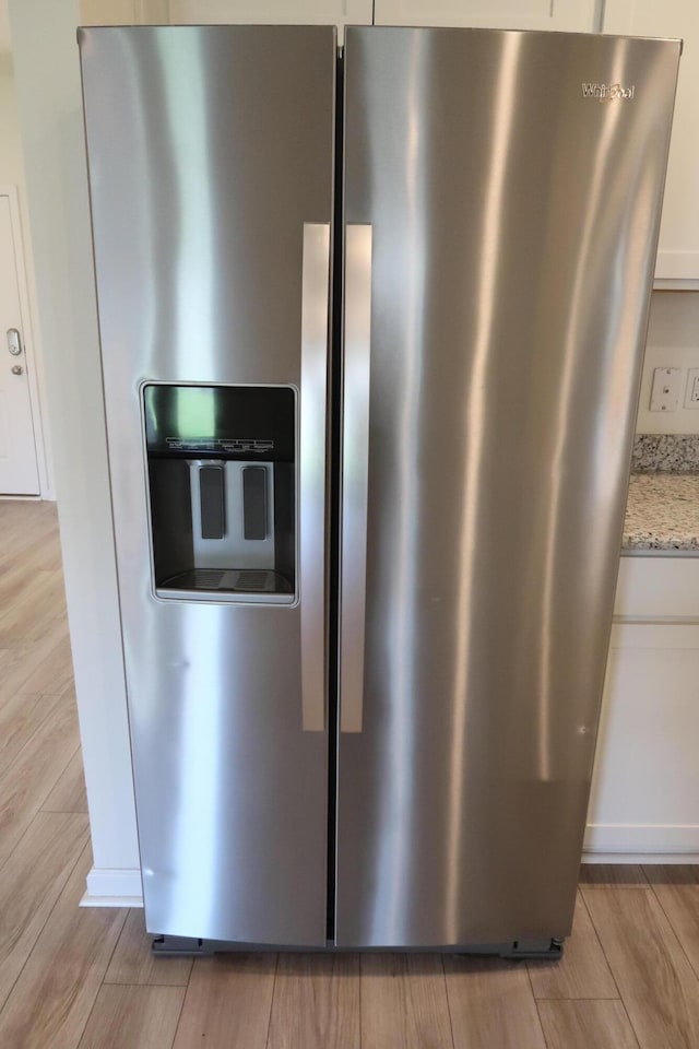 106 E Sky Way, Freeport, FL 32439 - kitchen view of stainless steel refrigerator with ice dispenser, light stone counters, light wood-style floors, and white cabinets