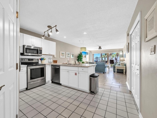 2606 Scenic Gulf Dr Unit 3208, Miramar Beach, FL 32550 - kitchen with stainless steel appliances, a peninsula, open floor plan, white cabinets, and a textured ceiling