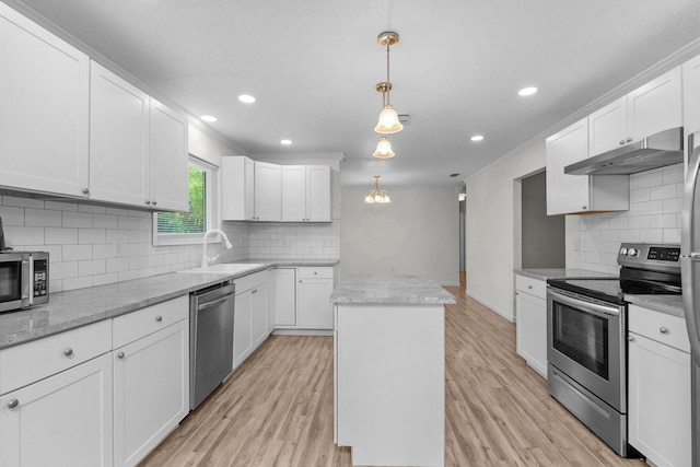 709 Russell Blvd, Fort Walton Beach, FL 32547 - kitchen featuring appliances with stainless steel finishes, under cabinet range hood, a kitchen island, tasteful backsplash, and ornamental molding