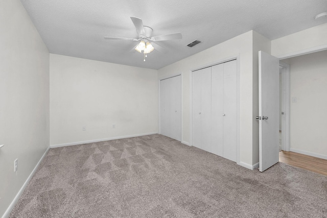 709 Russell Blvd, Fort Walton Beach, FL 32547 - unfurnished bedroom featuring carpet, two closets, baseboards, a textured ceiling, and ceiling fan
