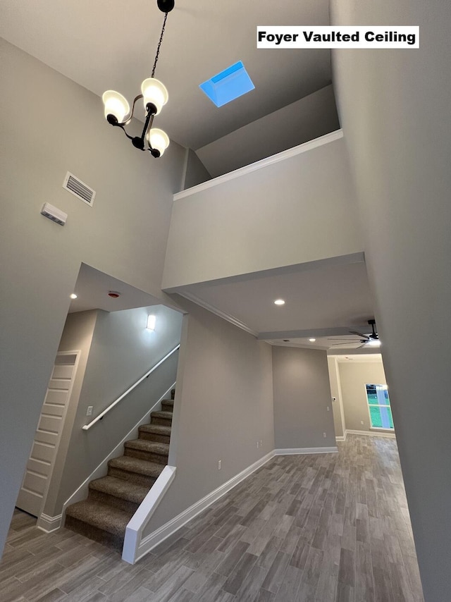 2675 Brodie Ln, Crestview, FL 32536 - stairs with wood finished floors, a towering ceiling, baseboards, a ceiling fan, and a chandelier