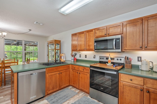 5420 Flag Tail Ln, Crestview, FL 32539 - kitchen with stainless steel appliances, a sink, a peninsula, light wood-style floors, and a textured ceiling