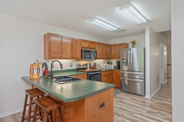 5420 Flag Tail Ln, Crestview, FL 32539 - kitchen with stainless steel appliances, a sink, a peninsula, a textured ceiling, and brown cabinets
