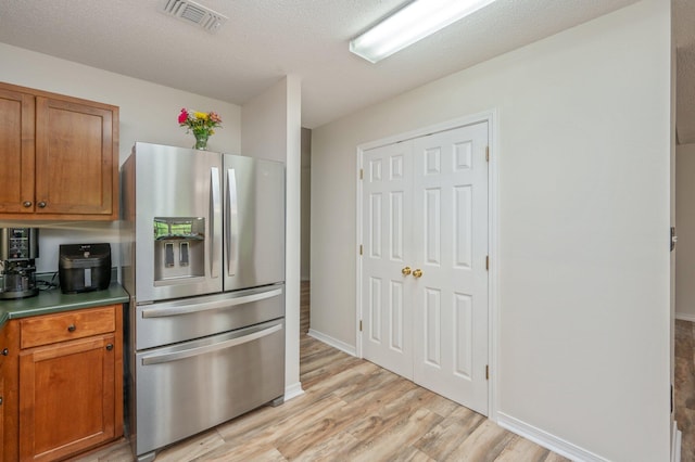 5420 Flag Tail Ln, Crestview, FL 32539 - kitchen featuring stainless steel fridge, light wood finished floors, brown cabinets, baseboards, and a textured ceiling