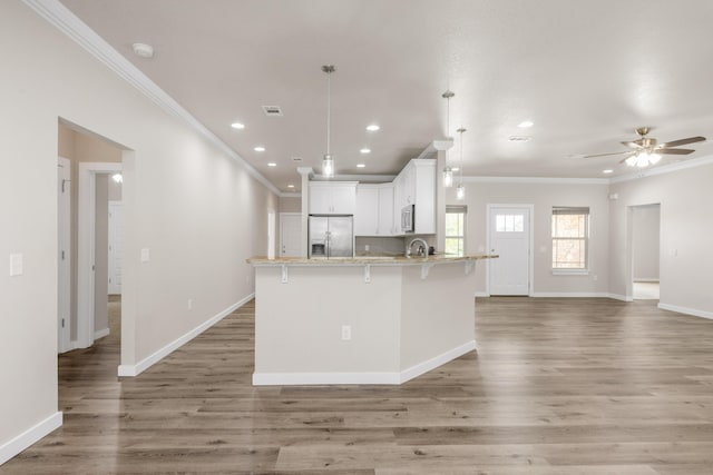 6437 Amanda Ct, Crestview, FL 32536 - kitchen with appliances with stainless steel finishes, ornamental molding, white cabinetry, a kitchen breakfast bar, and a peninsula