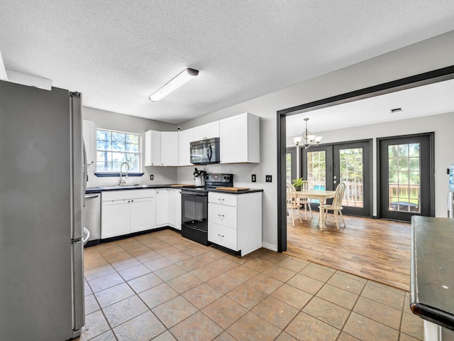 3241 Auburn Rd, Crestview, FL 32539 - kitchen featuring black appliances, a chandelier, light tile patterned flooring, white cabinetry, and a textured ceiling