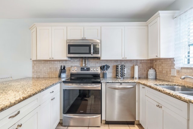 25 Misty Cv Unit 115, Miramar Beach, FL 32550 - kitchen with stainless steel appliances, decorative backsplash, white cabinets, and light stone counters